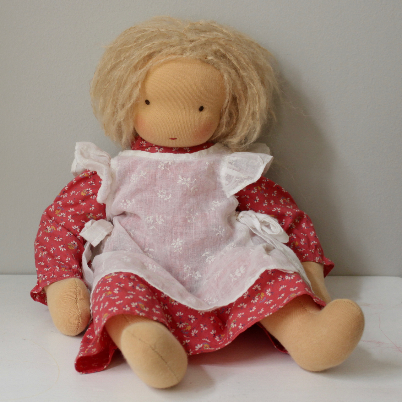 Waldorf doll girl in red dress and white apron, blond hair, made by feinslieb