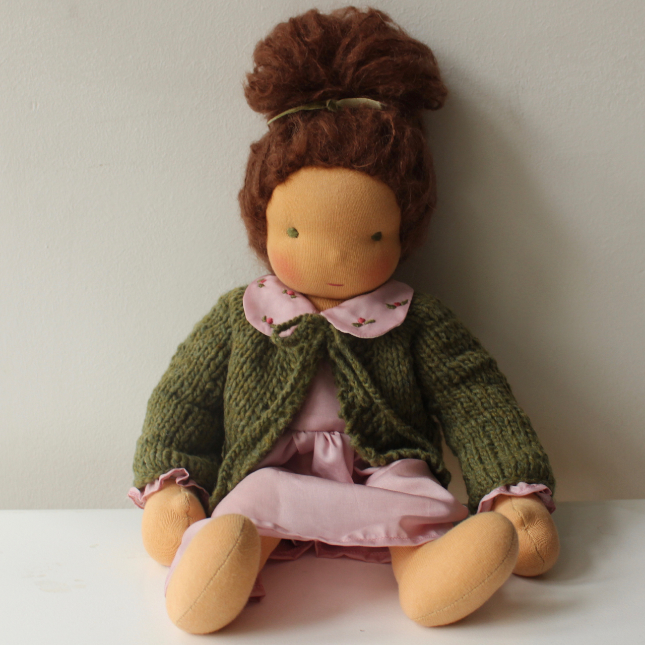 Waldorf doll girl in pink dresss, brown hair, green hand-knitted cardigan, made by feinslieb