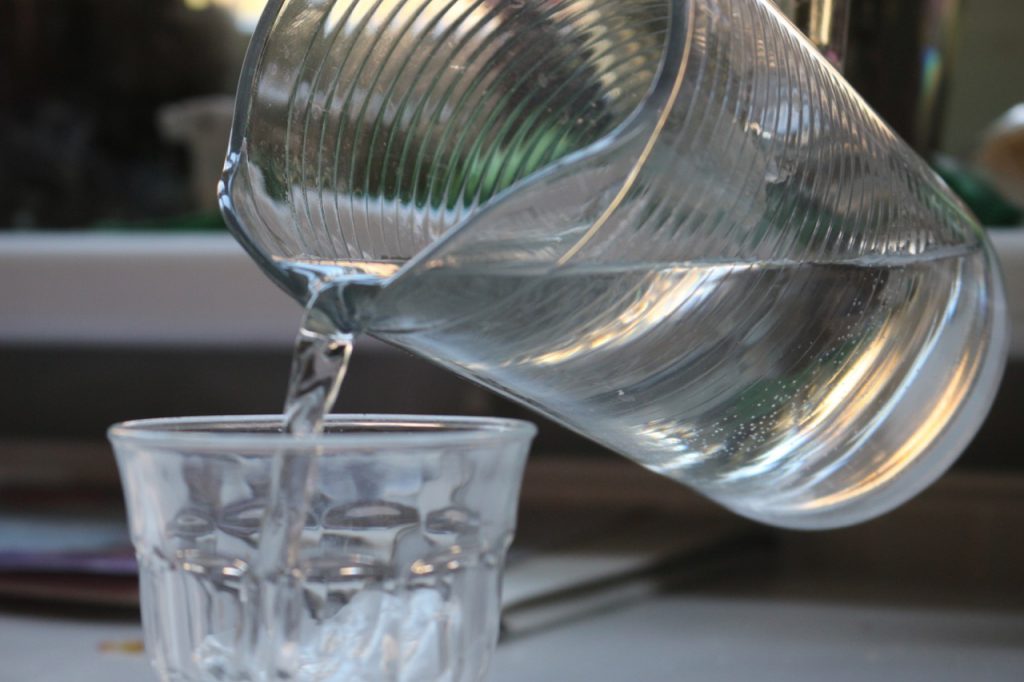 Wasser fließt aus Wasserkanne in Glas, Nahaufnahme