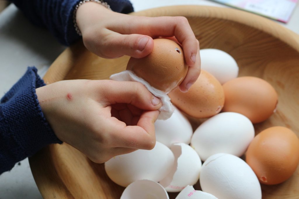Kinderhand reibt ausgeblasene Eier mit Tuch ab.