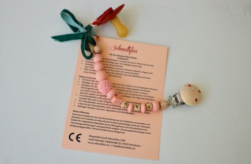 Warnhinweise Schnullerketten: Beipackzettel mit allen wichtigen Infos im Postkarten-Format; die Schnullerkette ist daran mit einer Schleife befestigt.