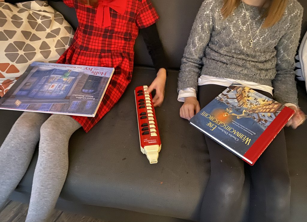 2 Weihnachtsbücher auf dem Schoß von 2 Mädchen, die auf dem Sofa sitzen (ohne Gesichter im Bild)