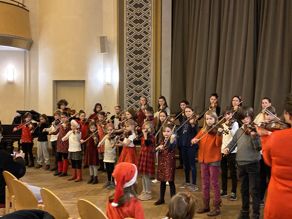 30 Kinder spielen Geige als Chor aufgestellt