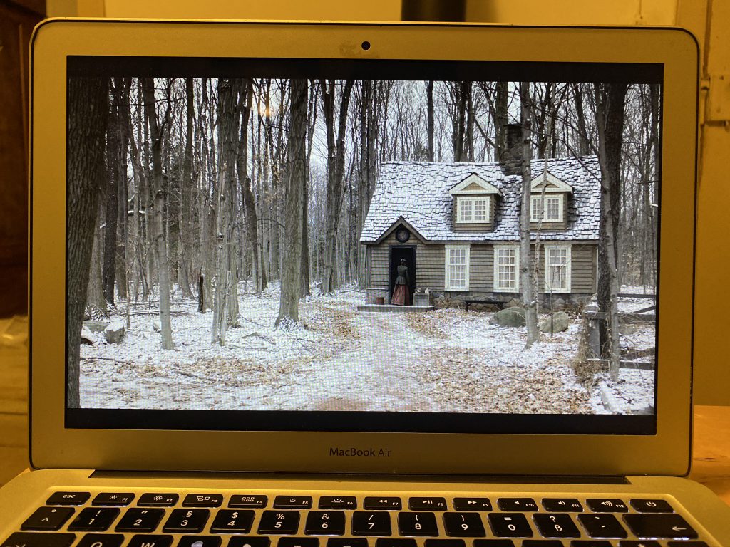 Computerbildschirm mit Szene aus "Anne with an E" (weiß beschneites Haus im Wald)