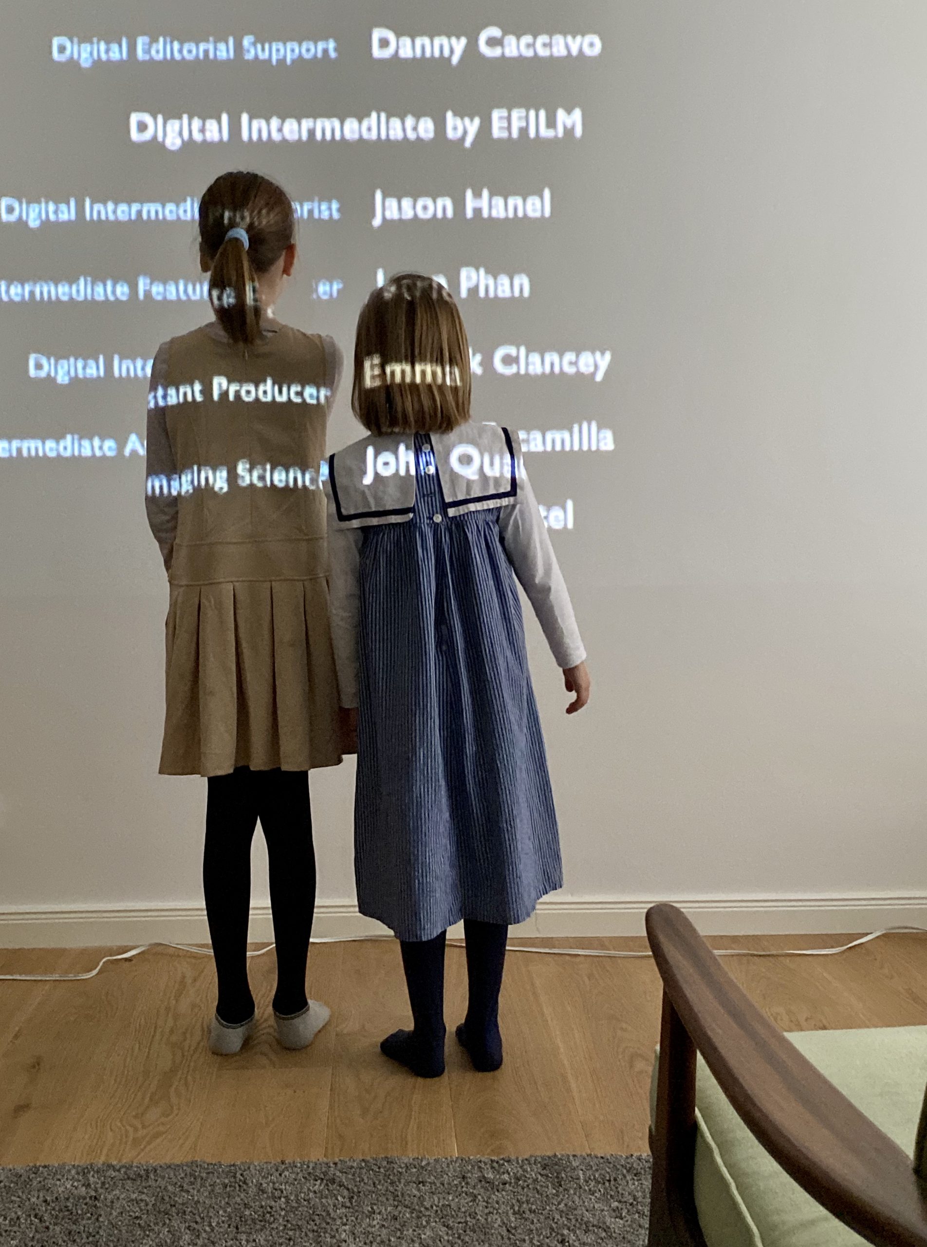 2 Kinder stehen vor Buchstaben an Wand von Filmprojektion