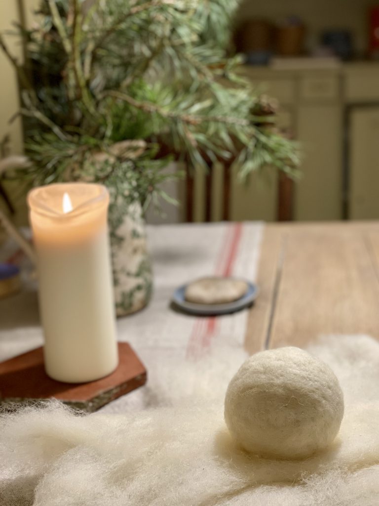 Wollkugel auf Holztisch vor weißer Kerze