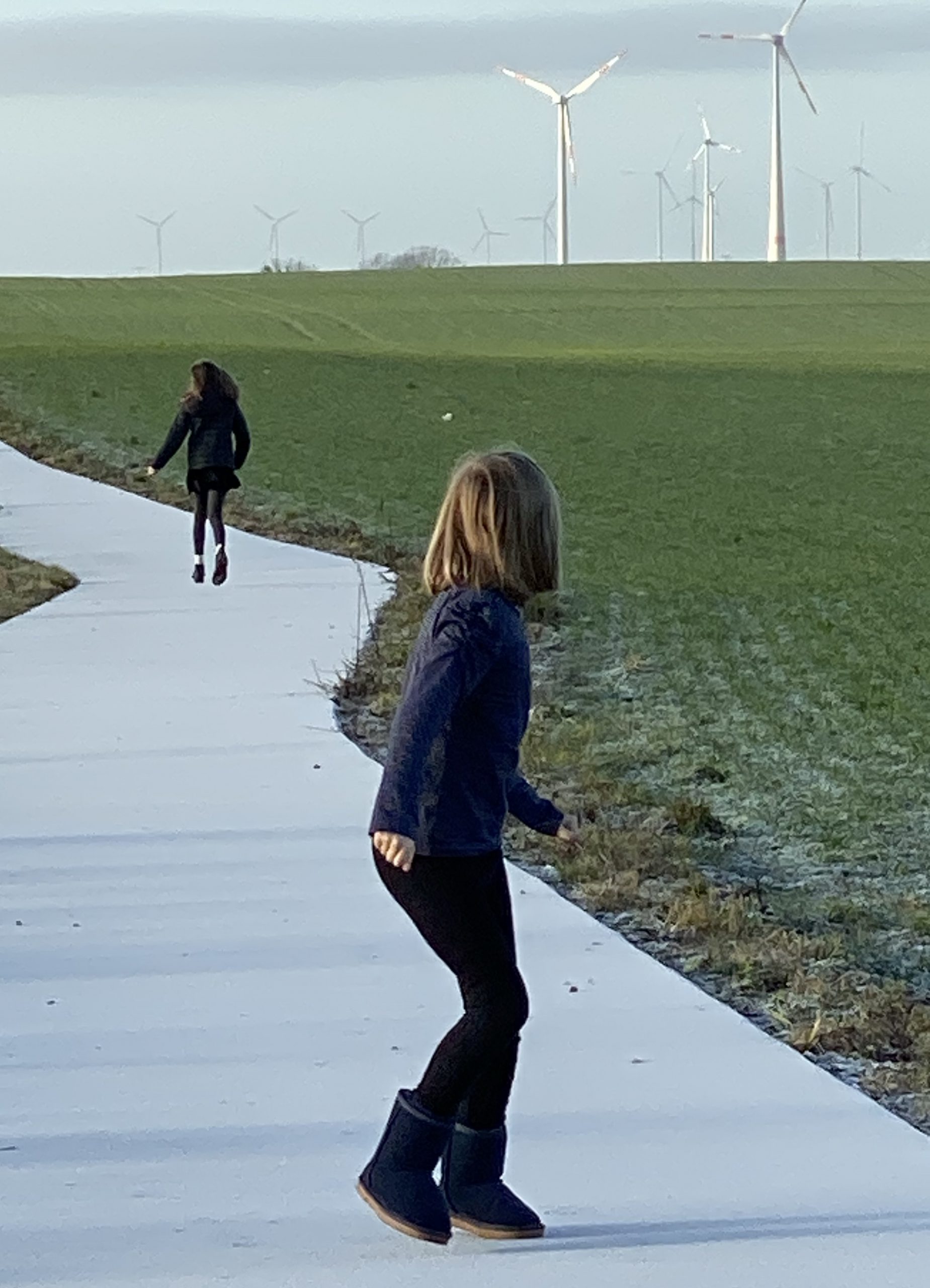 Zwei Kinder auf vereistem Weg neben grünem Feld