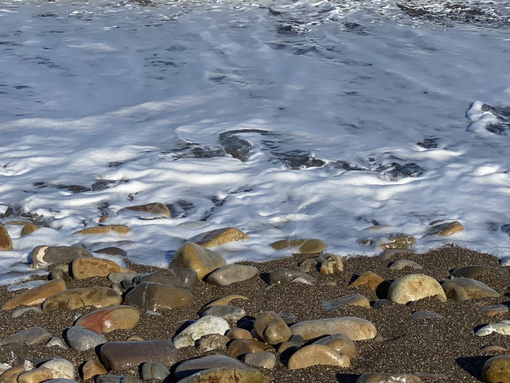 Wasser fließt an Steinen vorbei auf Sand