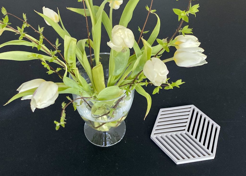 Blumenstrauß auf Tisch, daneben Topfuntersetzer mit Geometrie-Form