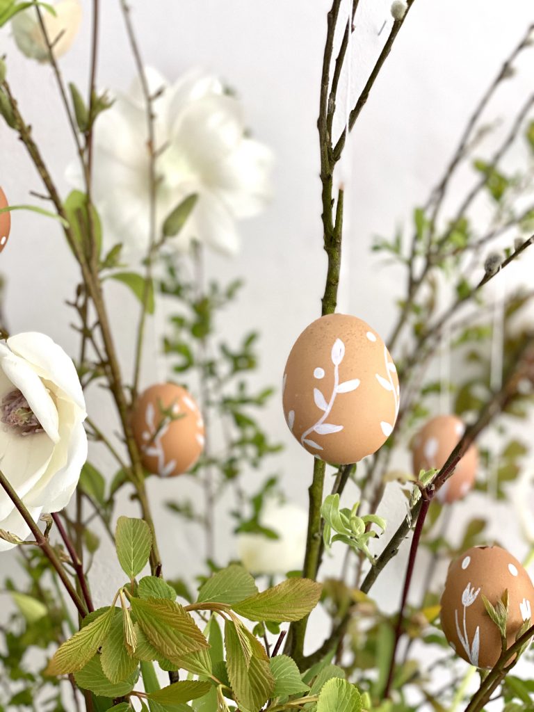 braune Eier am Osterstrauß mit weißer Verzierung (Blumenranke)