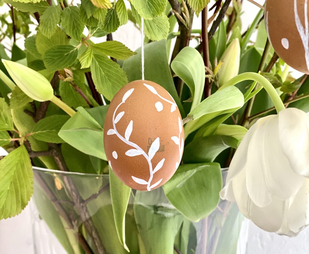 Braune Eier am Osterstrauß mit weißer Verzierung (Blumenranke)