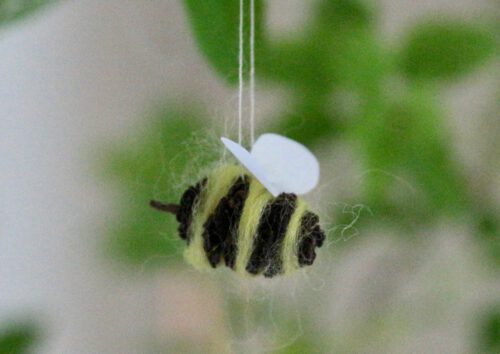 Biene basteln aus Erlenzapfen, vor Grün