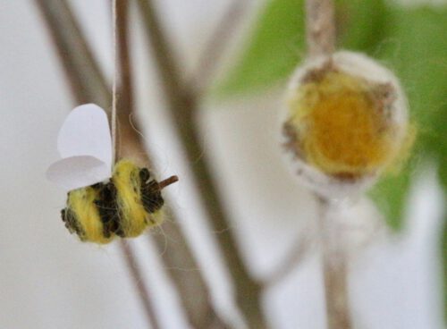 selbst gebastelte Biene aus Erlenzapfen an Zweig aufgehängt