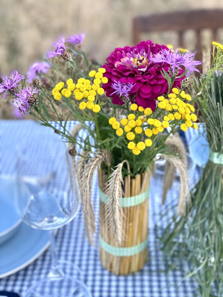 Basteln mit Getreide: Mit Getreideähren ummanteltes Glas mit bunten Sommerblumen drin, nah