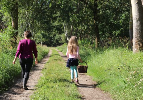 Maike und Tochter auf einem Waldweg, mit Korb in der Hand