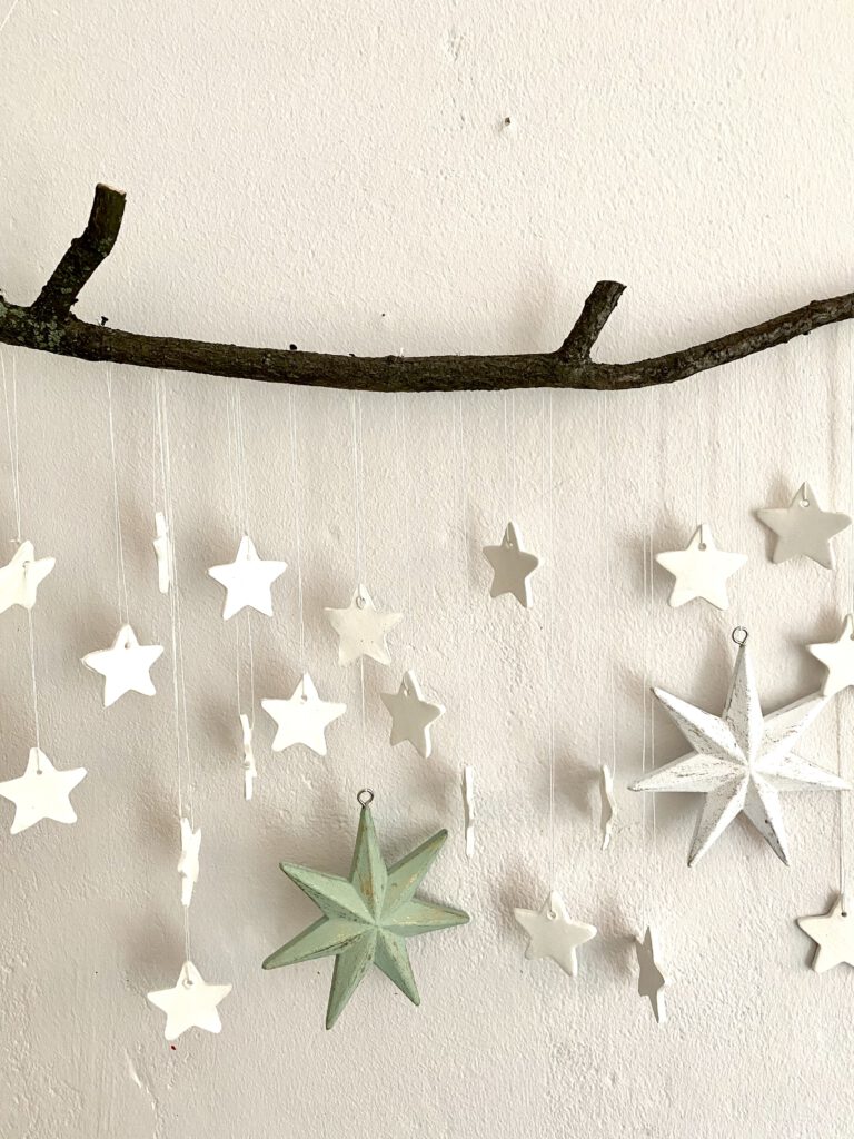 Mobile mit Sternen an einer weißen Wand: Detail mit ca. 15 weißen und 1 großen hellgrünen Stern 