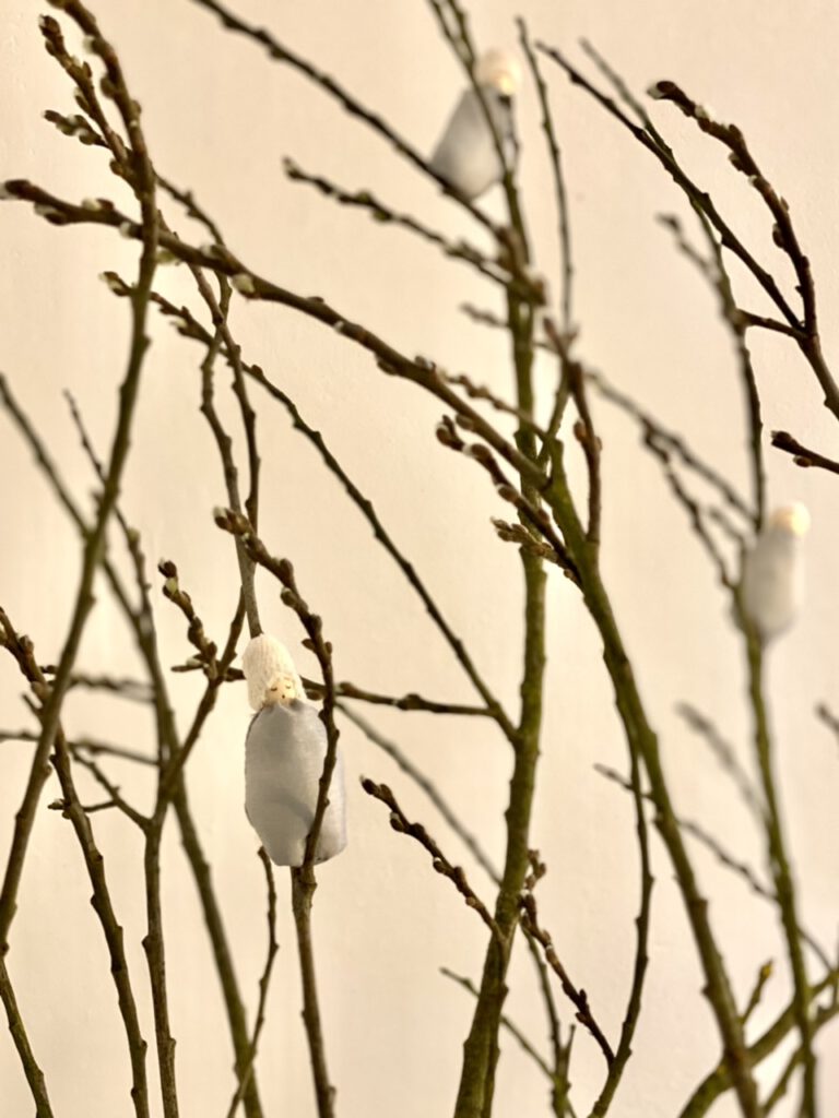 Drei Weidenkätzchen-Blumenkinder in Astgabeln eines großen Weidenzweigs steckend