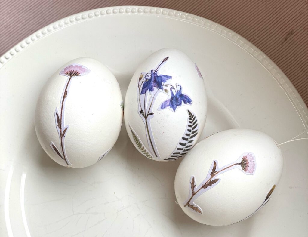 Teller mit drei Eiern, die mit Blumenmotiven beklebt sind