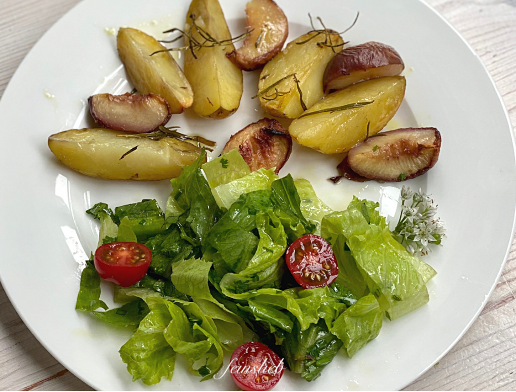 Gebackene Rosmarinkartoffeln mit Pfirsich auf Teller, mit grünem Salat