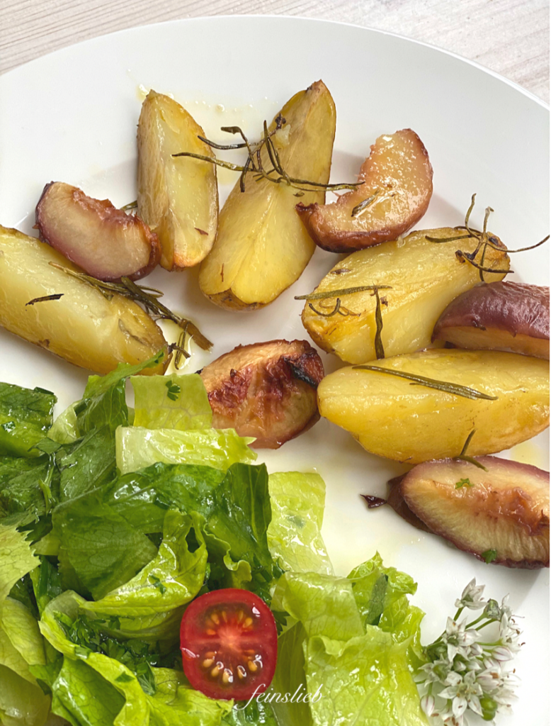 Gebackene Rosmarinkartoffeln mit Pfirsich auf Teller, mit grünem Salat.