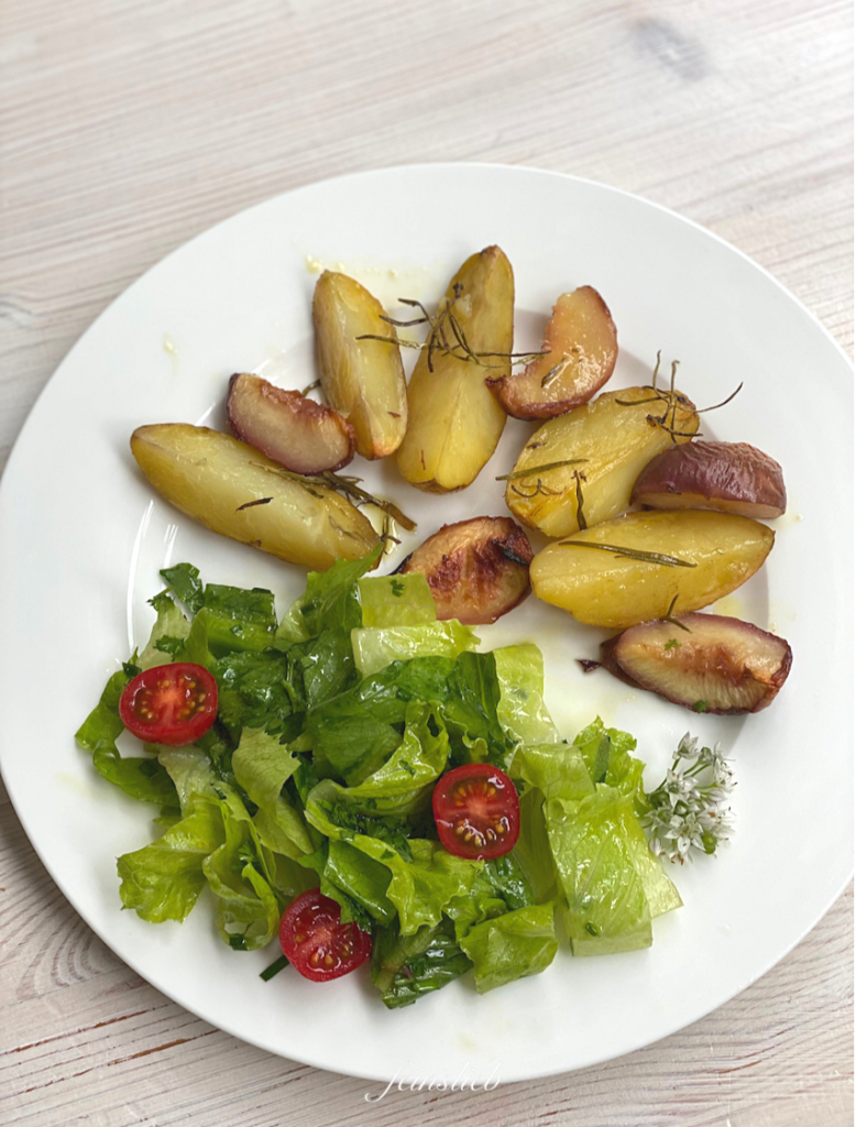 Gebackene Rosmarinkartoffeln mit Pfirsich auf Teller, mit grünem Salat daneben