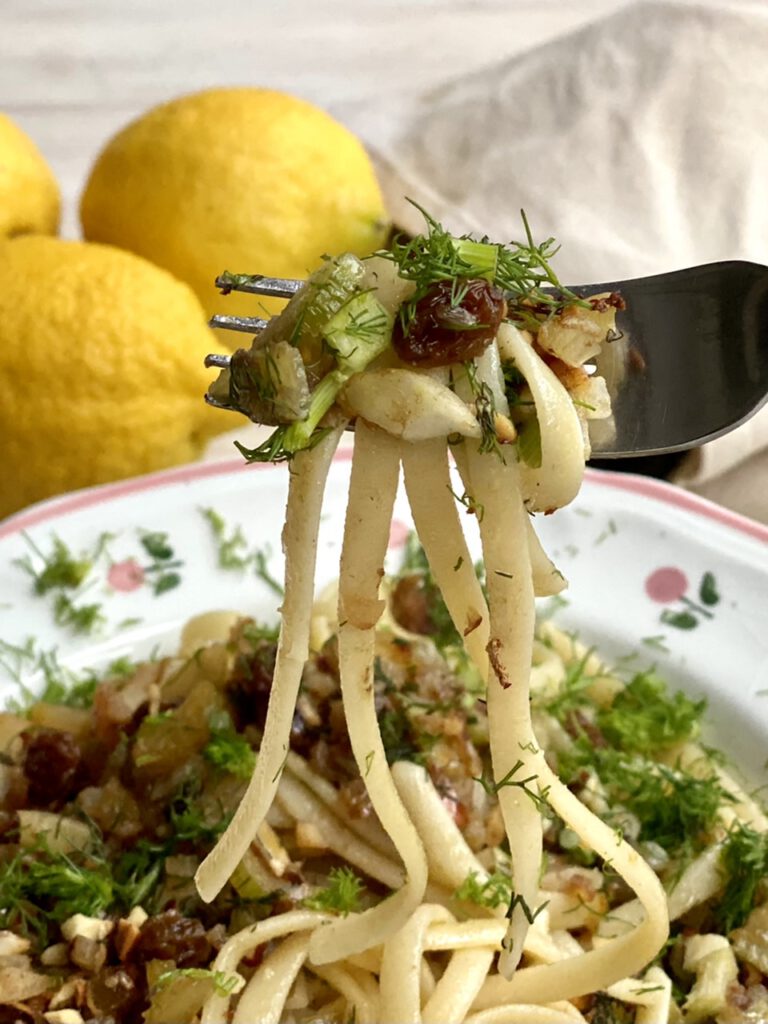 Gabel mit pasta con le sarde, im Hintergrund Zitronen