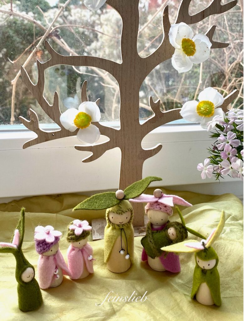 Blumenelfen Familie von oben vor Blütenstrauß und Hiolzbaum mit Blüten (Jahreszeitentisch Frühling)