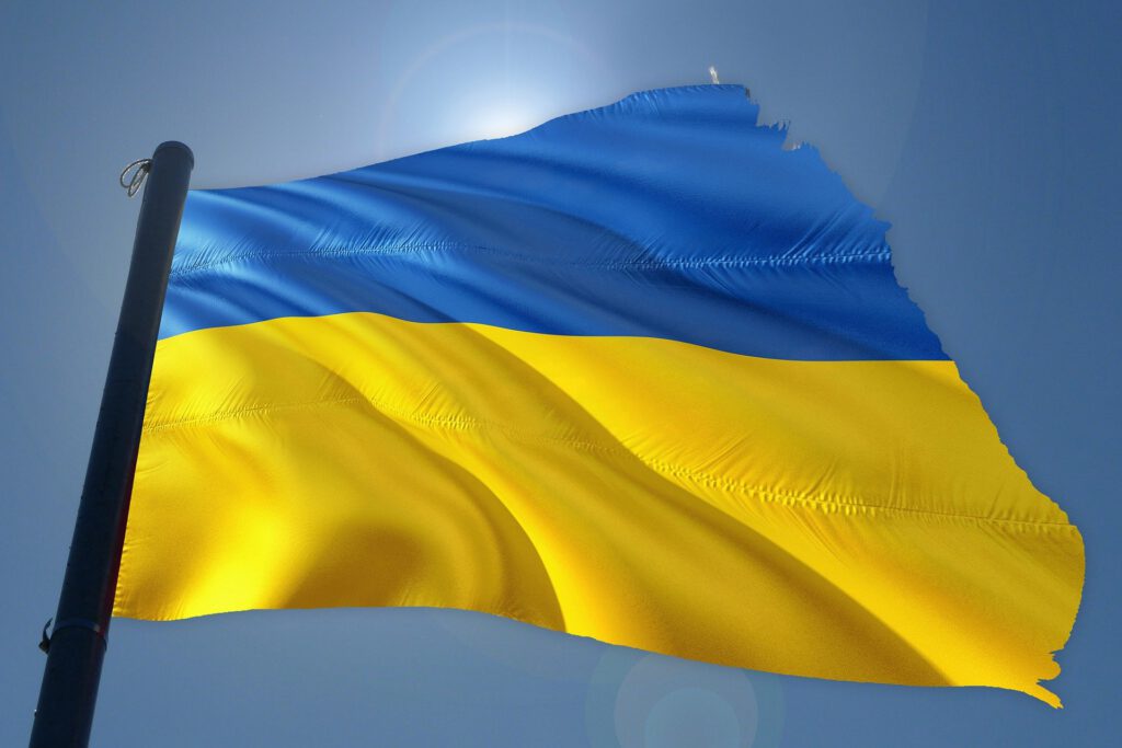 Wie kann ich der Ukraine helfen? Ukrainische Flagge vor blauem Himmel