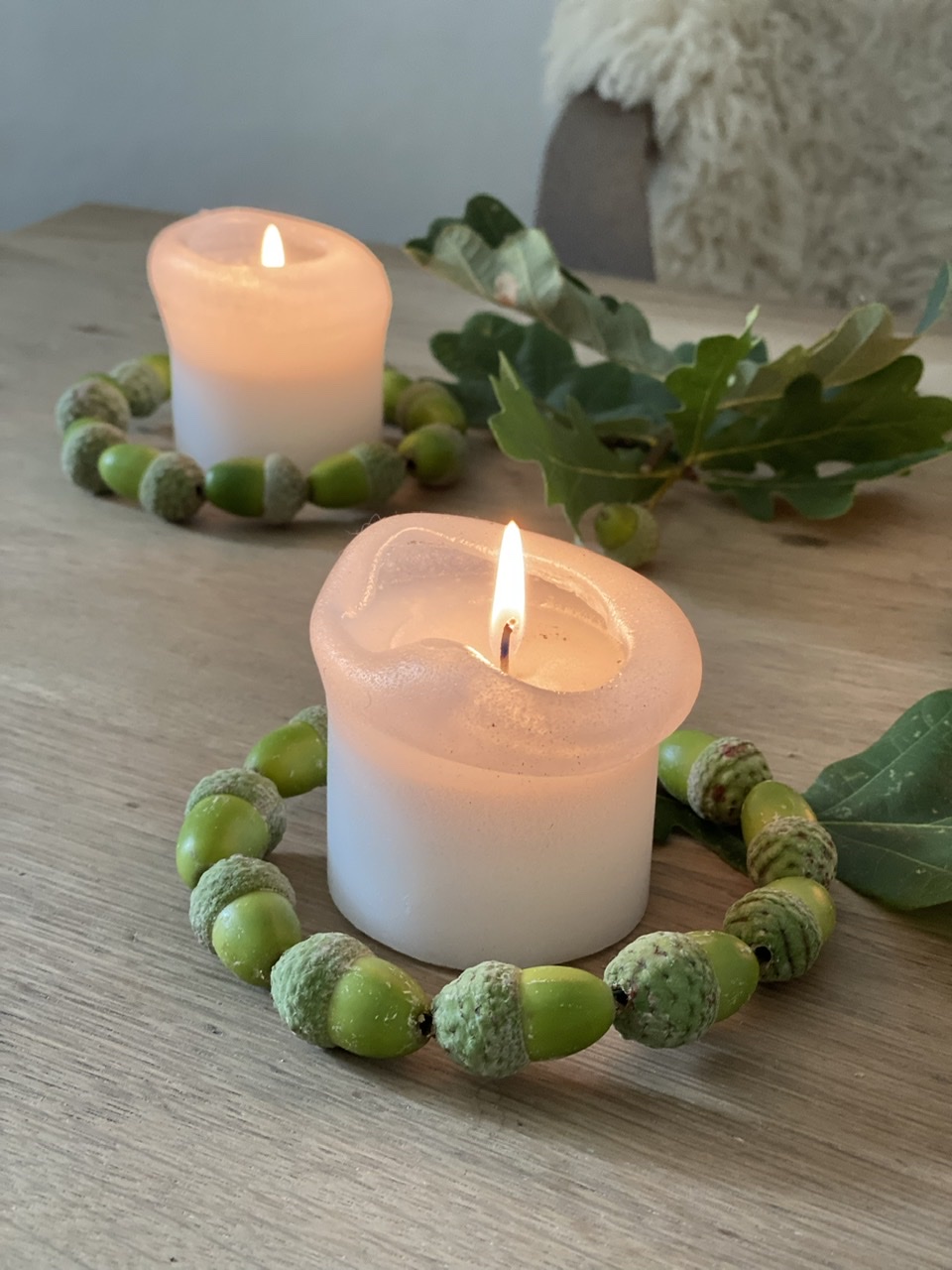 Basteln mit grünen Eicheln Idee 3: Drei Kränze aus "hintereinander liegenden" grünen Eicheln um drei Kerzen