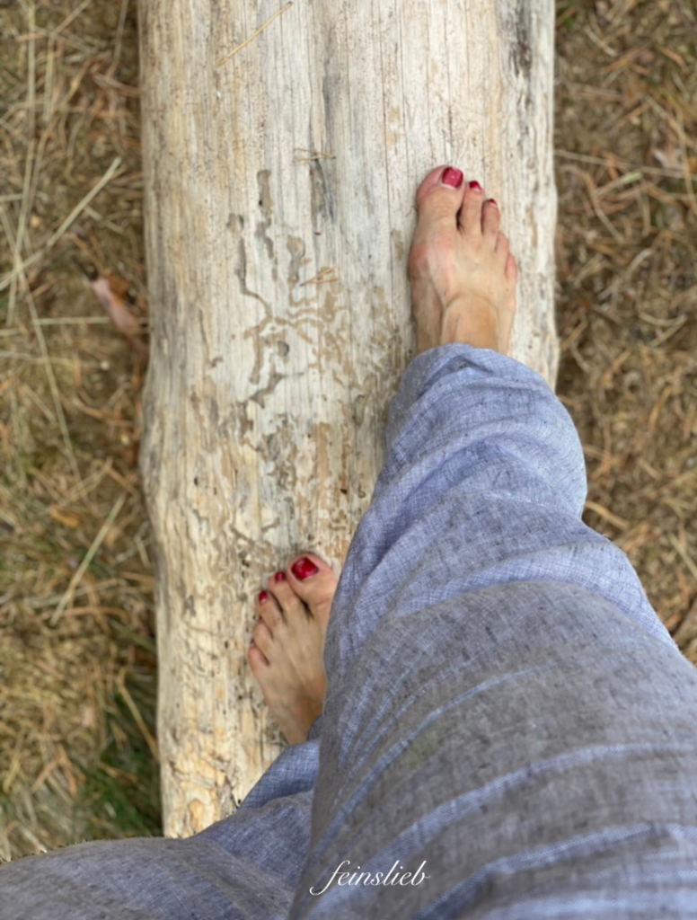Barfüßige Füße auf einem Holzstamm von oben