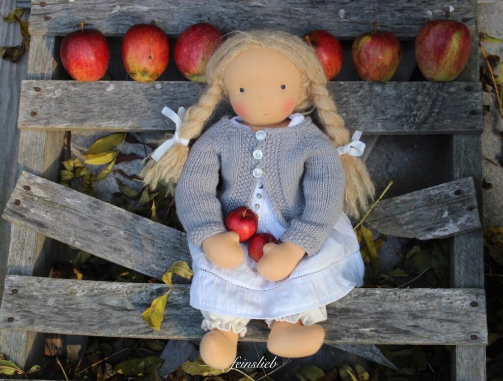 Oktober mit Kindern - Ideen: WaldorfPuppe auf Holzleiter mit roten Äpfeln im schoß