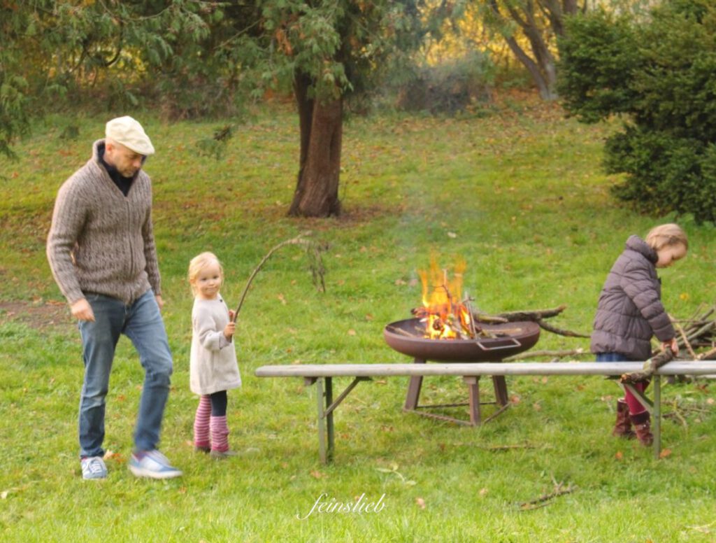 Familie macht Feuer im Garten (in Feuerschale) - (September Ideen für Aktivitäten mit Kindern)