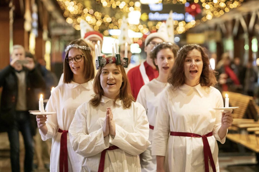 Lucia feiern: Lucia Umzug in Straße in Schweden (weiß gekleidete Mädchen mit Kerzen und Lichterkranz