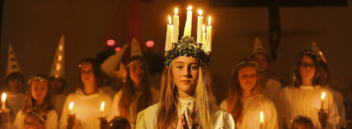 Eine Lucia Braut mit weißem Kleid und Lichterkrone (Kerzen)