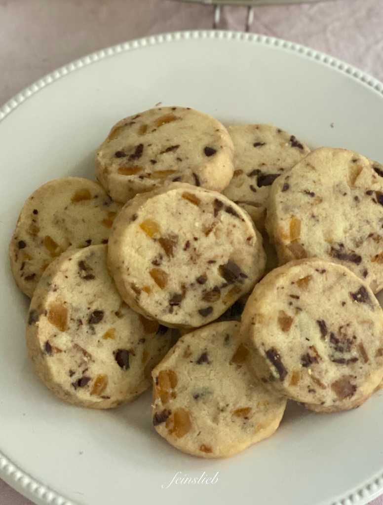 Rezept Shortbread Cookies mit Orange und Schokolade auf weißem Teller und rosa Tischdecke