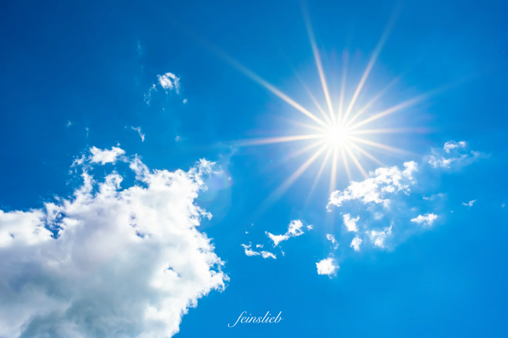 Weiße Juli-Sonne am blauen Himmel und kraftvolle Wolken